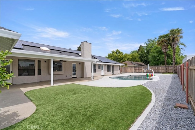exterior space featuring a fenced backyard, ceiling fan, a yard, and roof mounted solar panels