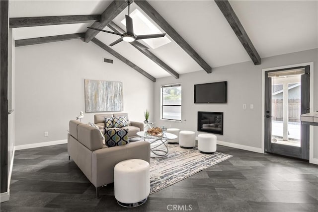 living area with lofted ceiling with beams, a glass covered fireplace, a ceiling fan, baseboards, and visible vents