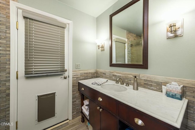 5580 Bromely Dr, Oak Park, CA 91377 - bathroom featuring wood finished floors, tile walls, a shower, wainscoting, and vanity