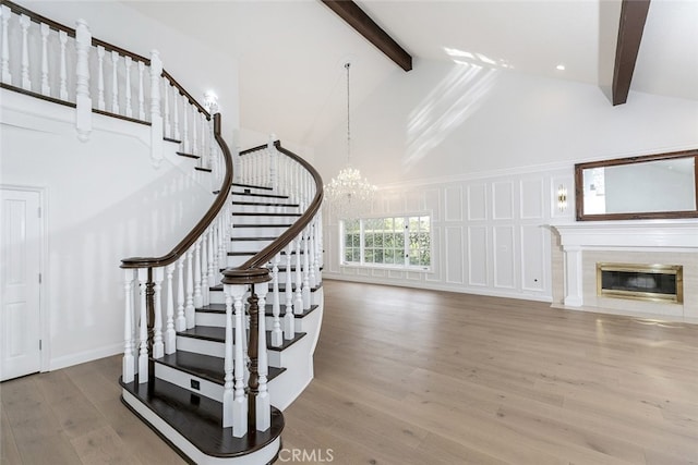 stairs featuring beamed ceiling, a chandelier, wood finished floors, and high vaulted ceiling