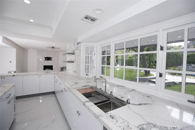 kitchen featuring visible vents, light stone counters, marble finish floor, white cabinetry, and a premium fireplace