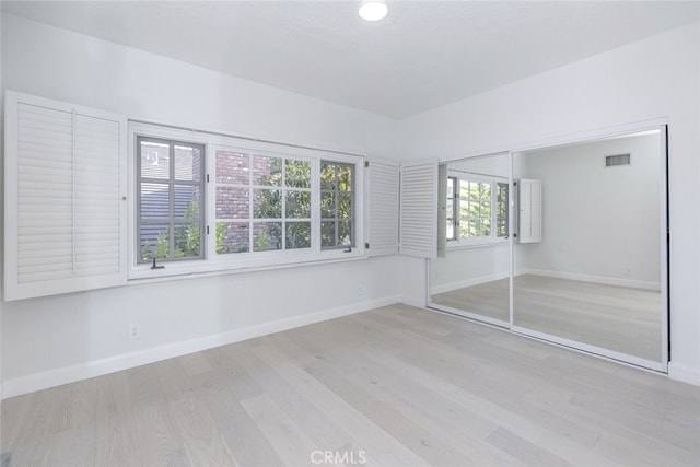 unfurnished bedroom featuring baseboards, visible vents, wood finished floors, and a closet