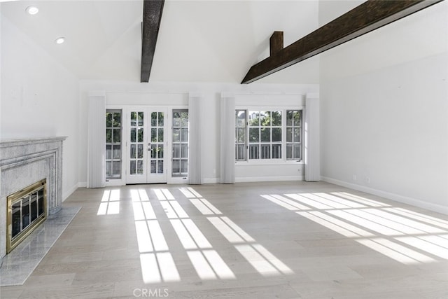 unfurnished living room featuring beam ceiling, wood finished floors, baseboards, recessed lighting, and a premium fireplace