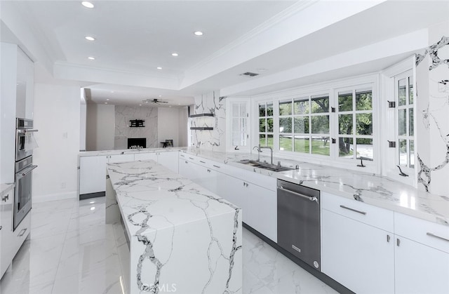 kitchen with appliances with stainless steel finishes, a center island, light stone countertops, a sink, and recessed lighting