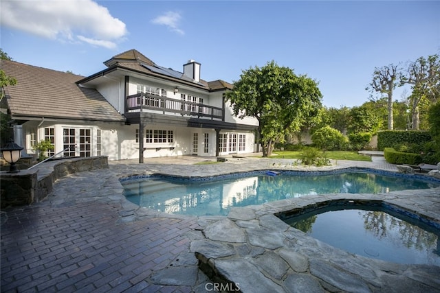 view of pool with french doors, a pool with connected hot tub, and a patio area