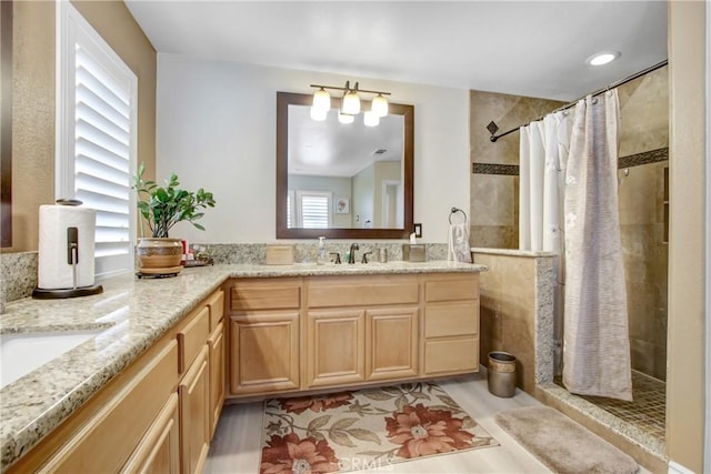 bathroom featuring double vanity, a sink, and a tile shower