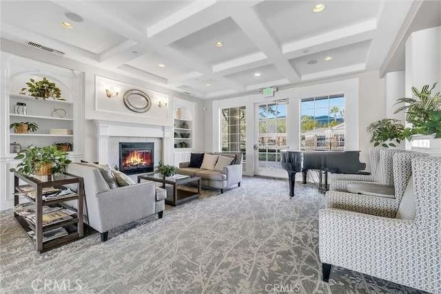 living room featuring carpet floors, visible vents, a glass covered fireplace, beam ceiling, and coffered ceiling