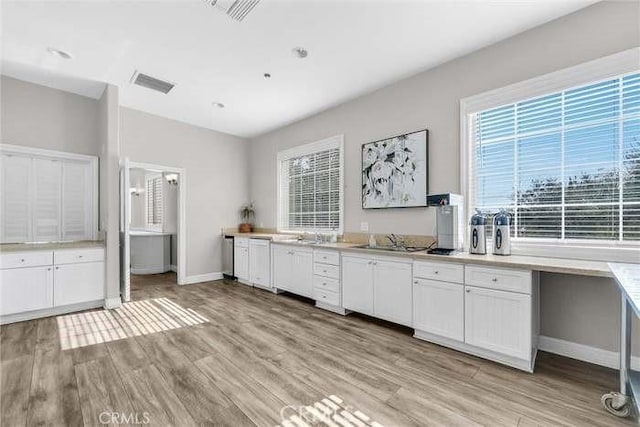 interior space featuring visible vents, light wood finished floors, a wealth of natural light, and white cabinetry