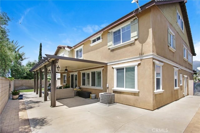 back of property with ceiling fan, stucco siding, a fenced backyard, central AC unit, and a patio