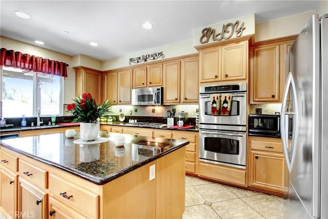 kitchen with a kitchen island, backsplash, light brown cabinetry, a sink, and stainless steel appliances