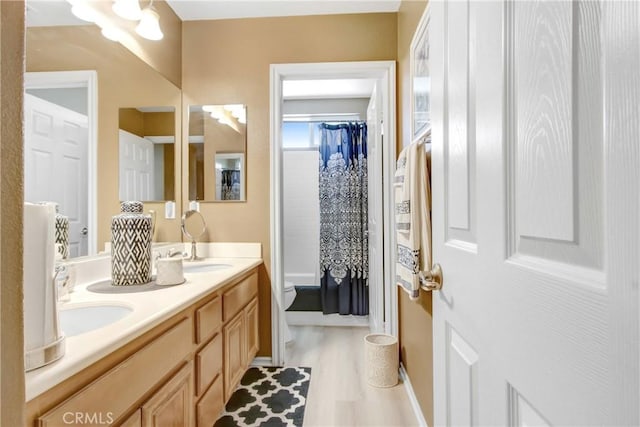 bathroom with double vanity, wood finished floors, curtained shower, toilet, and baseboards