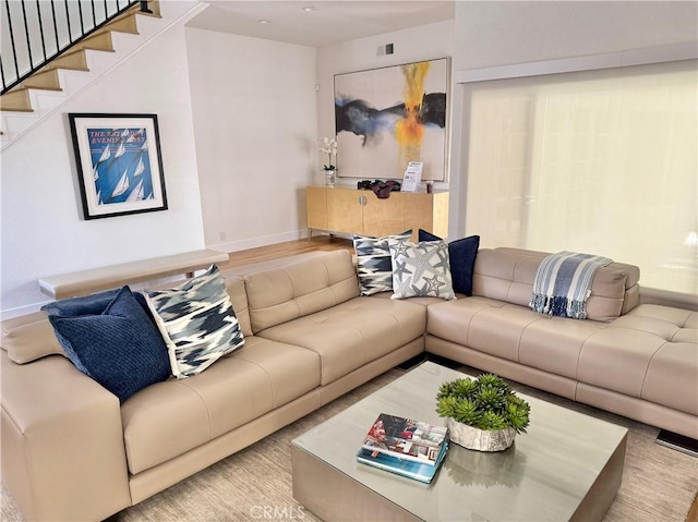 living area with baseboards, wood finished floors, and stairway