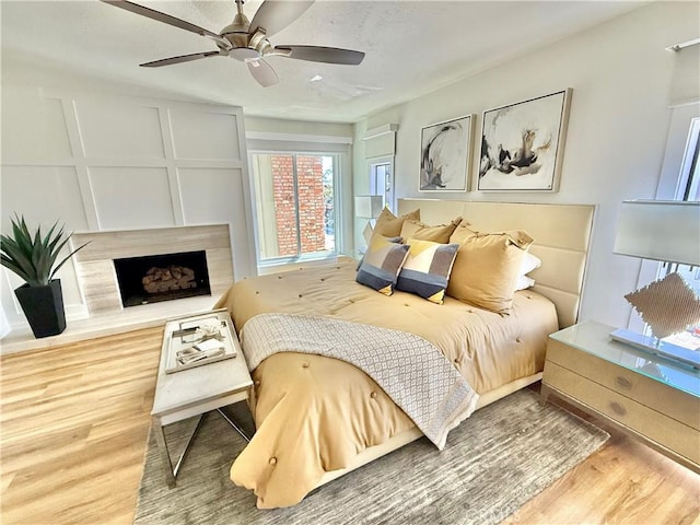 bedroom with a ceiling fan, wood finished floors, and a premium fireplace