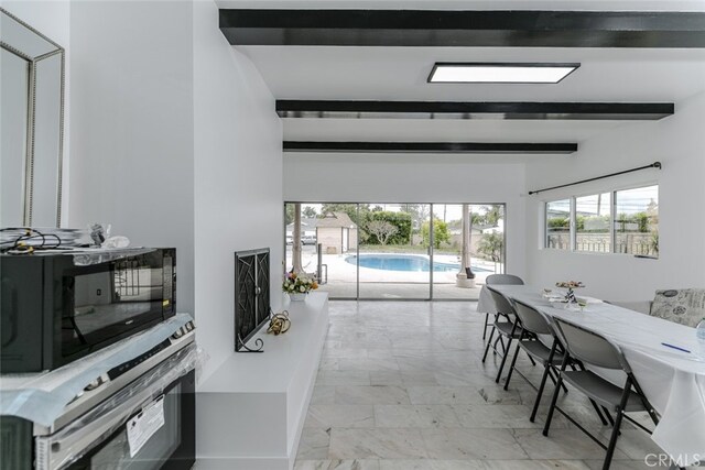 dining area featuring beam ceiling and marble finish floor