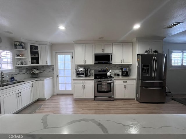 19522 Caney Ave, Carson, CA 90746 - kitchen featuring white cabinetry, tasteful backsplash, a sink, light wood finished floors, and stainless steel appliances