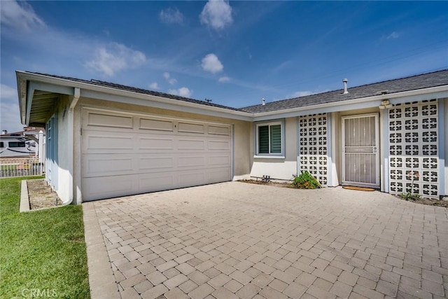 ranch-style house with stucco siding, an attached garage, and decorative driveway