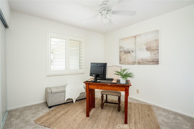 office space featuring baseboards, a ceiling fan, and light colored carpet