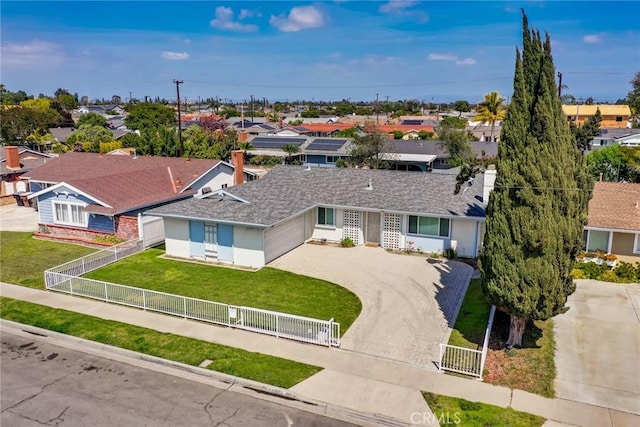 view of front of home featuring a front yard, an attached garage, a fenced front yard, driveway, and a residential view
