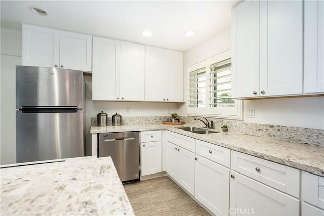 kitchen featuring recessed lighting, white cabinetry, light stone counters, a sink, and stainless steel appliances