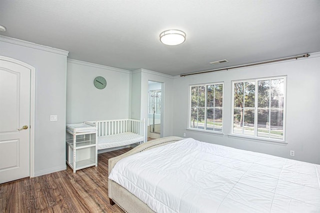 bedroom with crown molding, baseboards, and wood finished floors