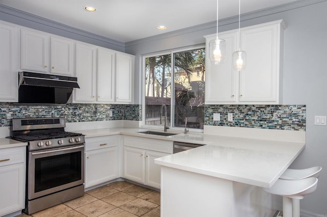 kitchen featuring a peninsula, stainless steel range with gas cooktop, under cabinet range hood, tasteful backsplash, and a sink