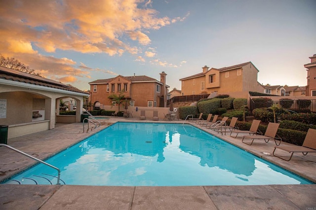 community pool with fence, a patio area, and a residential view