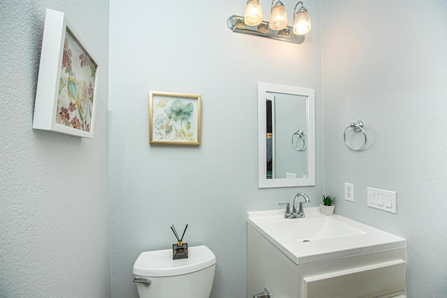 bathroom featuring toilet, a chandelier, and vanity