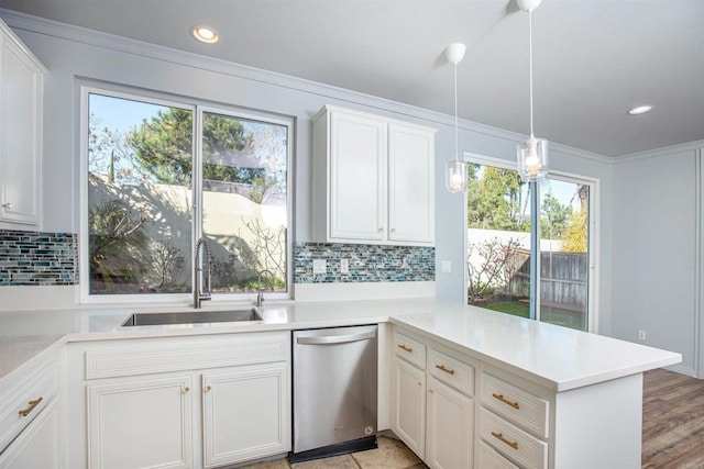 kitchen featuring stainless steel dishwasher, a peninsula, light countertops, tasteful backsplash, and a sink