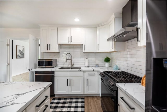 kitchen featuring decorative backsplash, white cabinetry, a sink, stainless steel appliances, and wall chimney exhaust hood