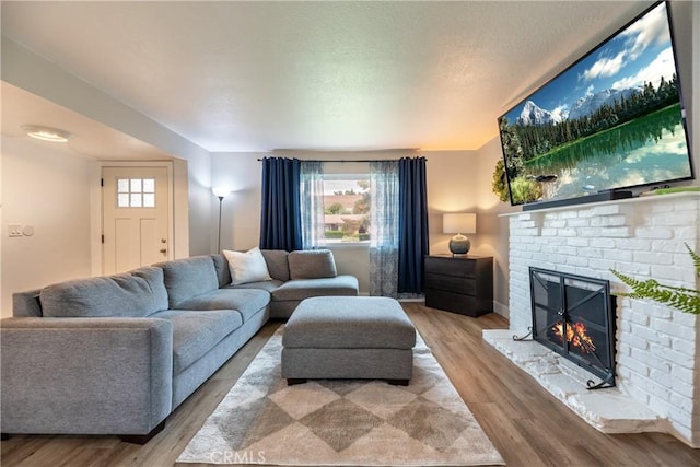 living room with baseboards, a brick fireplace, and wood finished floors