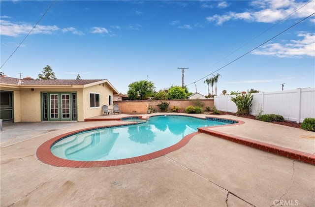 view of pool with a fenced in pool, a fenced backyard, an in ground hot tub, french doors, and a patio