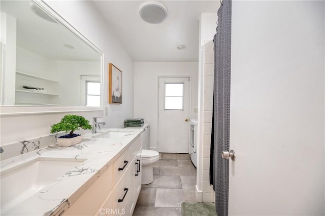 full bathroom with a sink, washer / dryer, toilet, and double vanity