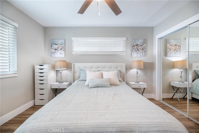 bedroom with baseboards, ceiling fan, a closet, and wood finished floors