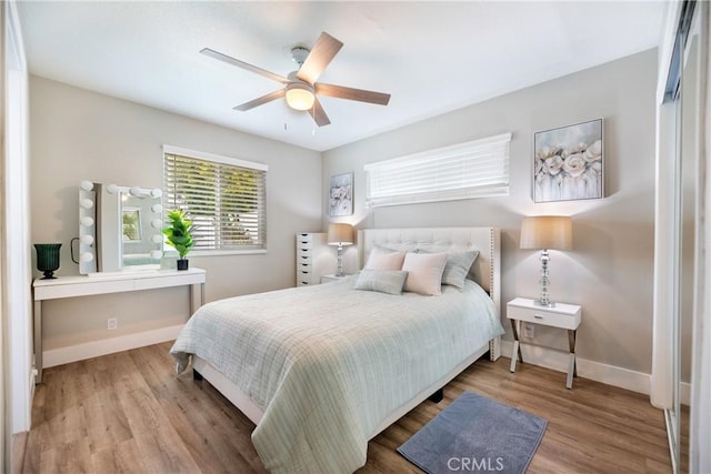 bedroom featuring a ceiling fan, baseboards, and wood finished floors