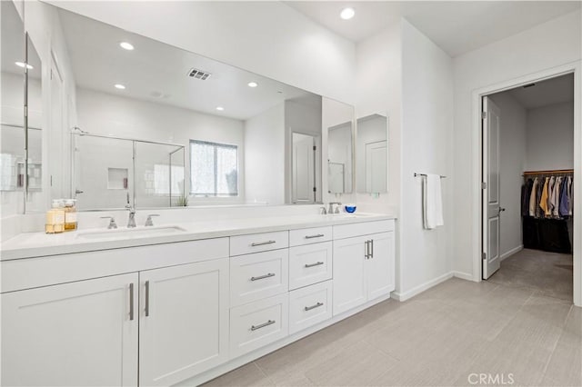 bathroom featuring double vanity, visible vents, a sink, and a stall shower