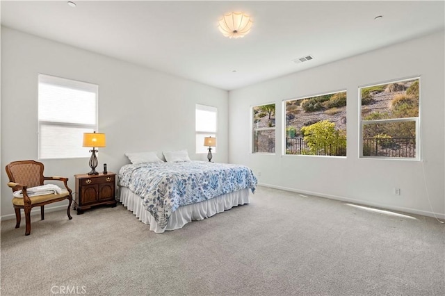 bedroom featuring visible vents, baseboards, and light carpet