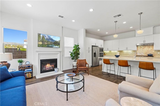 living room with dark wood-type flooring, recessed lighting, and visible vents