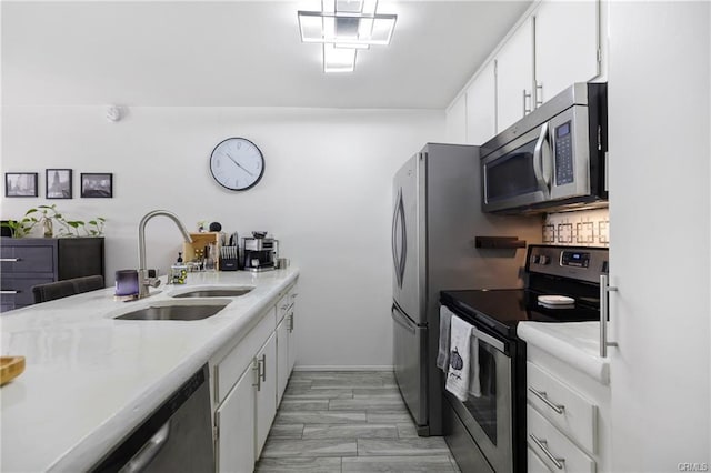 kitchen featuring a sink, light countertops, white cabinets, baseboards, and stainless steel appliances
