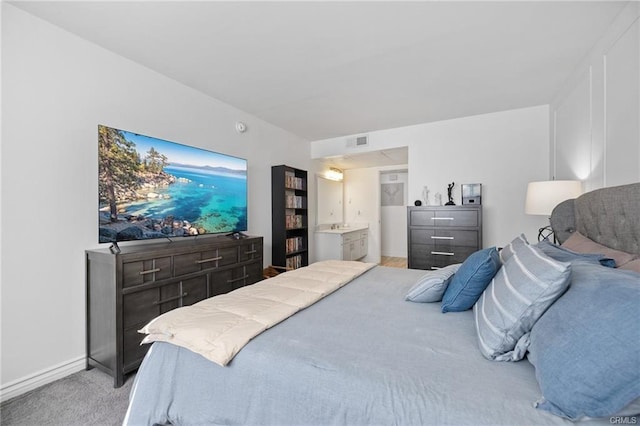 bedroom featuring baseboards, visible vents, light carpet, and ensuite bathroom