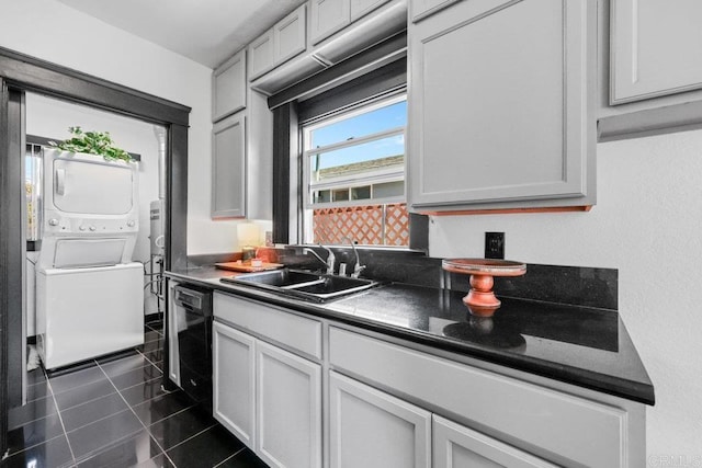 kitchen featuring a sink, dishwasher, stacked washer / dryer, and dark countertops