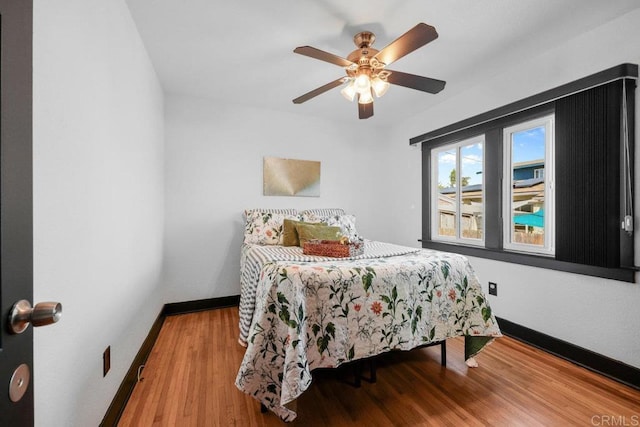 bedroom with a ceiling fan, baseboards, and wood finished floors
