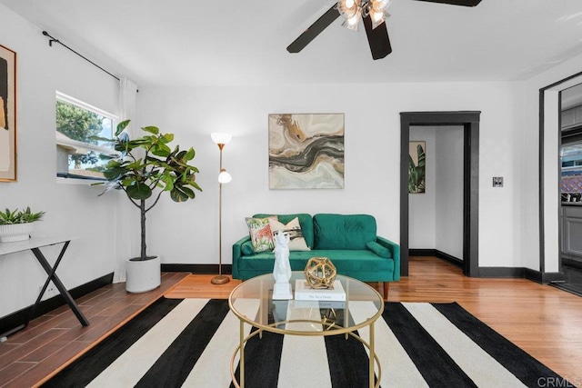 living area featuring baseboards, ceiling fan, and wood finished floors