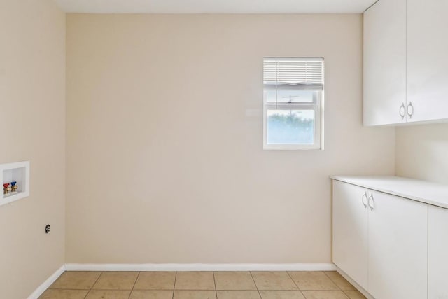 laundry room with light tile patterned floors, washer hookup, baseboards, and cabinet space