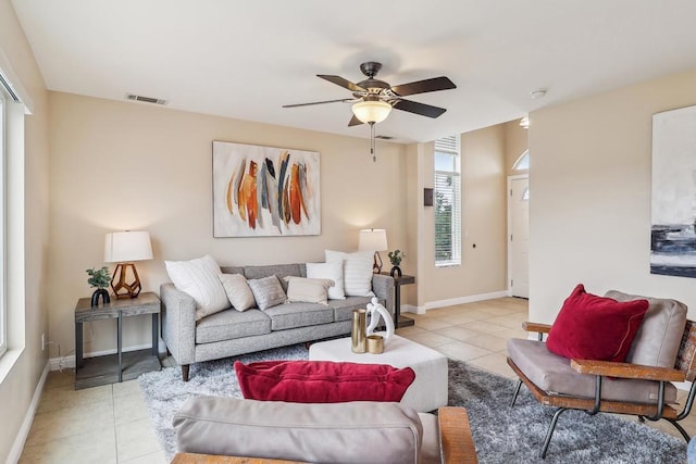 living area featuring light tile patterned flooring, ceiling fan, visible vents, and baseboards