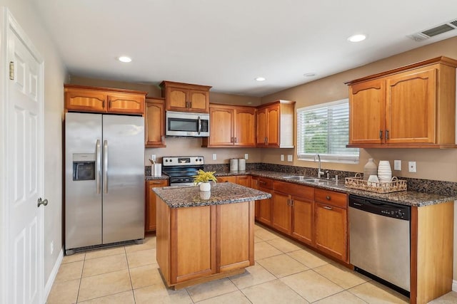 kitchen with visible vents, a center island, a sink, dark stone countertops, and stainless steel appliances