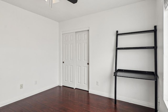 unfurnished bedroom featuring a ceiling fan, baseboards, wood finished floors, and a closet