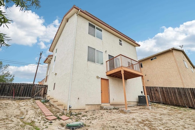 rear view of property featuring a fenced backyard, stucco siding, central AC, and a balcony