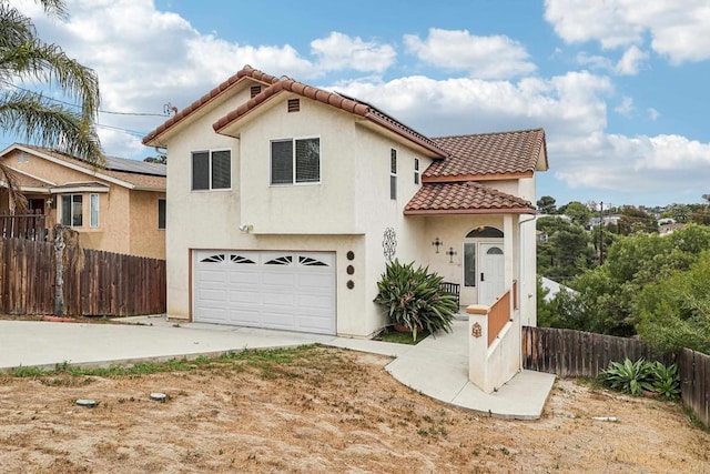 mediterranean / spanish-style home featuring a tile roof, a garage, fence, concrete driveway, and stucco siding