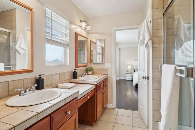 full bath with double vanity, baseboards, a shower stall, and a sink
