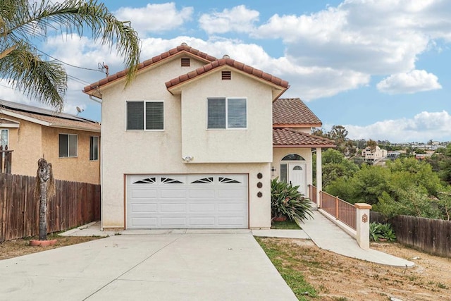 mediterranean / spanish-style home with fence, a garage, stucco siding, concrete driveway, and a tiled roof
